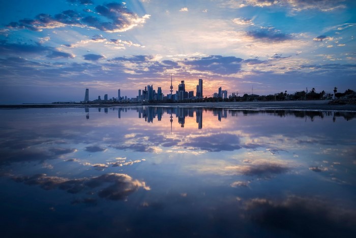 Kuwait City skyline reflected in the water at sunset