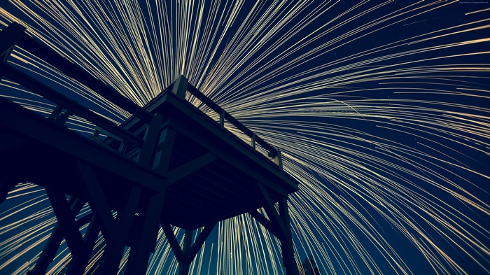 Wooden structure against a starry sky with light trails