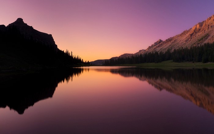 Mountain lake at sunset with purple and orange sky