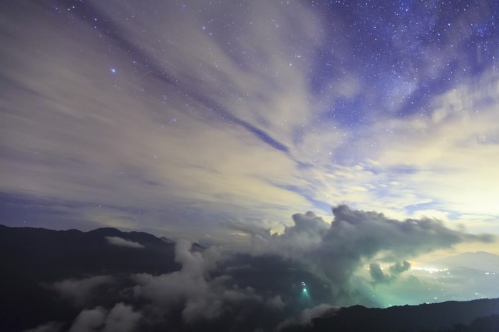 Night sky with stars and clouds over mountains