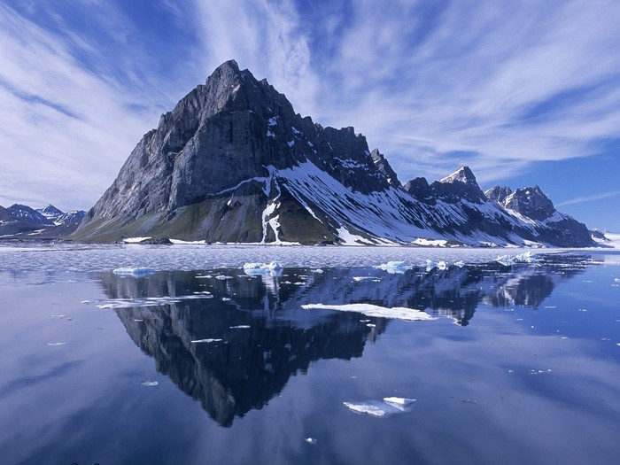 Snow-capped mountains reflected in a calm Arctic fjord