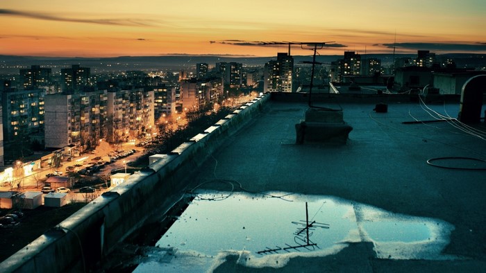 Rooftop view of a city at sunset with a puddle
