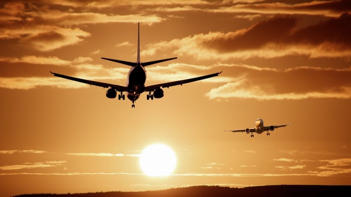 Two airplanes flying at sunset with clouds