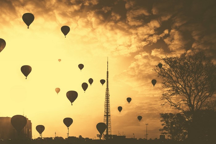 Hot air balloons over a city at sunset