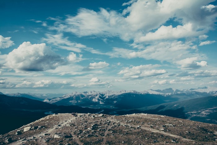 Mountain range with clouds and hikers on a rocky summit