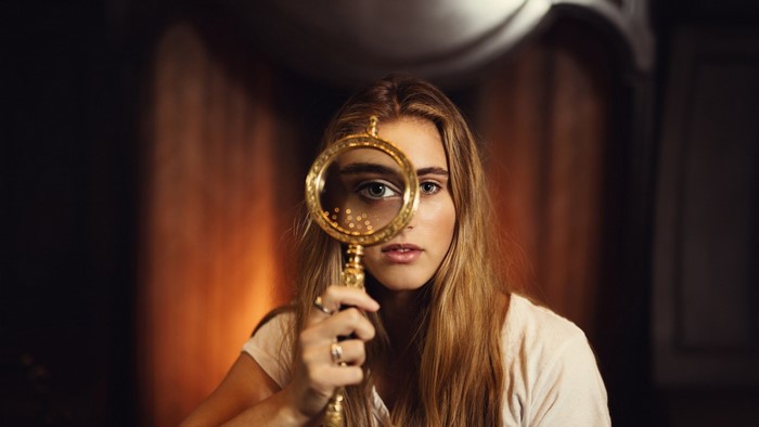Woman looking through a magnifying glass
