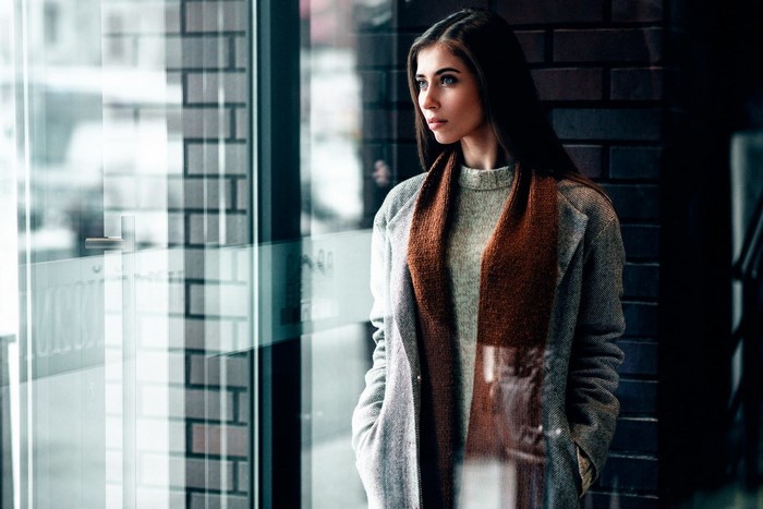 Woman in coat and scarf looking out window