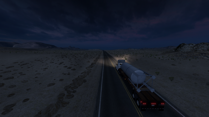 Truck hauling a tank trailer on a desert highway at night