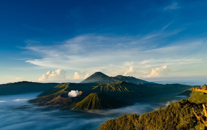 Volcanoes shrouded in mist under a blue sky