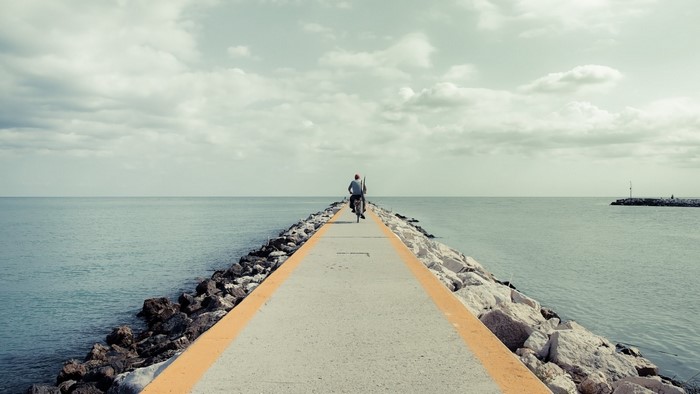 Man riding bicycle on a pier over the sea