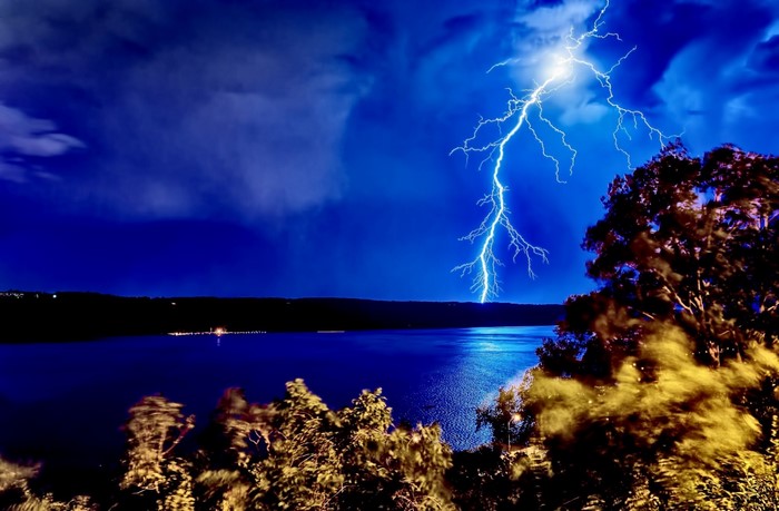 Lightning strike over a body of water at night