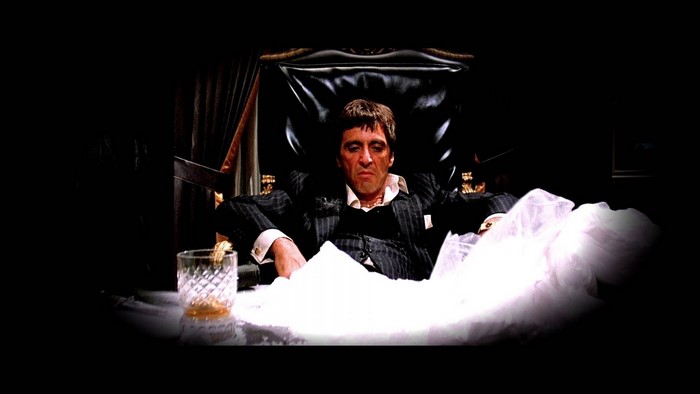 Tony Montana from Scarface sitting with cocaine