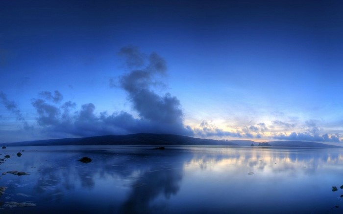 Calm lake reflecting a cloudy sky at dusk