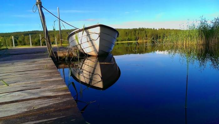 White boat docked on a wooden pier by a calm lake