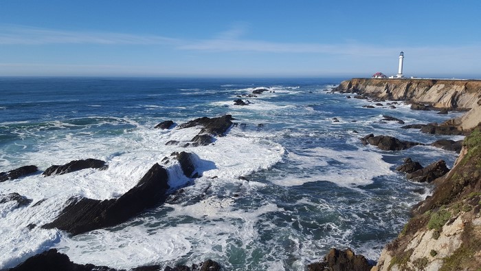 Lighthouse on a rocky coast with waves crashing