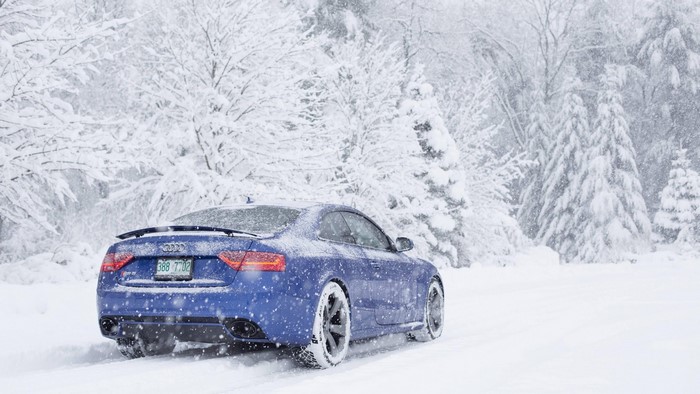 Blue Audi RS5 driving in a snowstorm