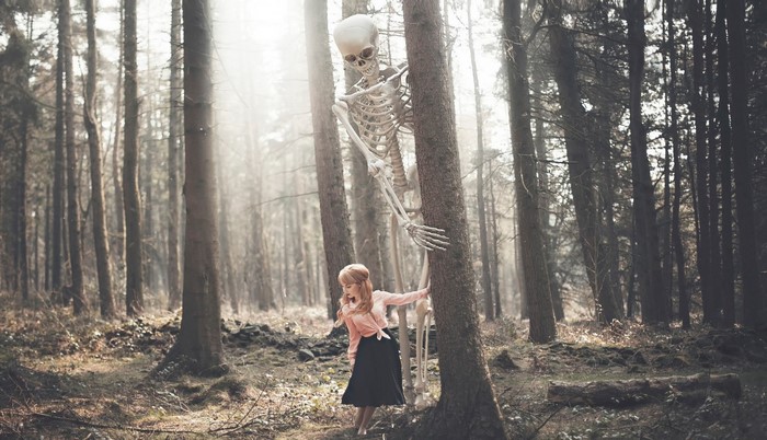 Skeleton behind a woman in a forest