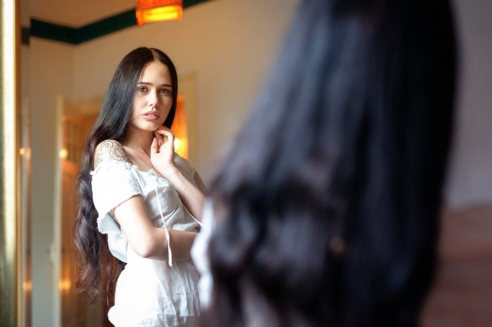 Woman looking in a mirror with a tattoo