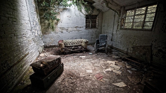 Abandoned room with couch and wheelchair