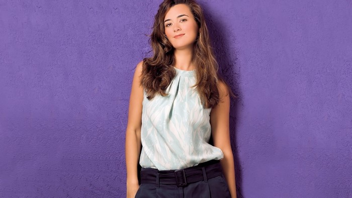 Cote de Pablo standing against a purple wall