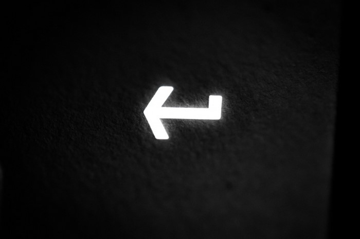 Close-up of a glowing white Enter key on a black keyboard