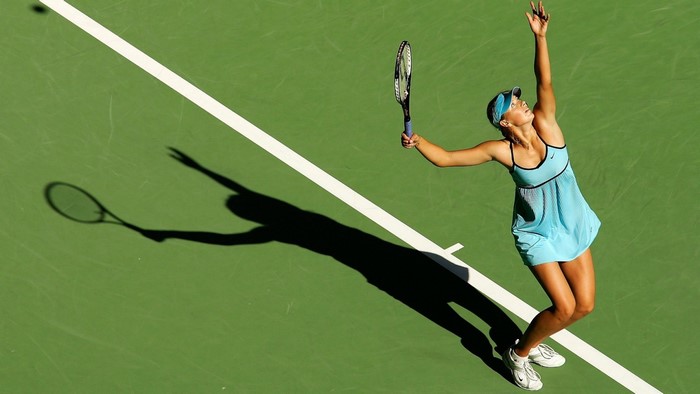 Maria Sharapova serving a tennis ball on a court