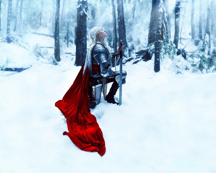 Woman in armor with red cape in snowy forest