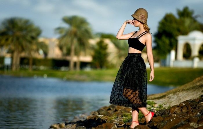 Woman in black dress and hat by the water