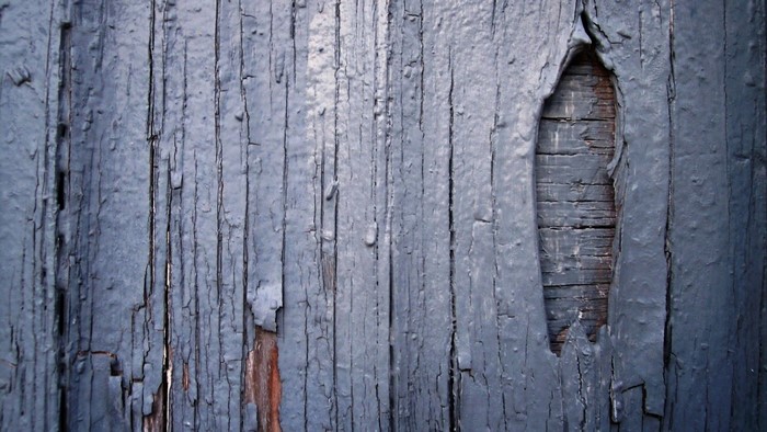 Cracked blue painted wooden planks with a hole