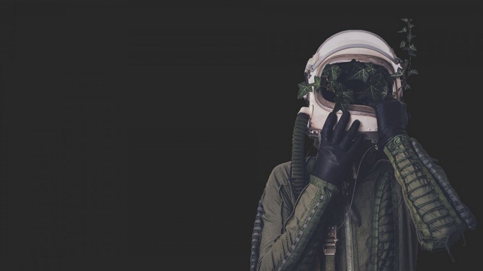 Surreal Pilot with Plant-Filled Helmet in Darkness
