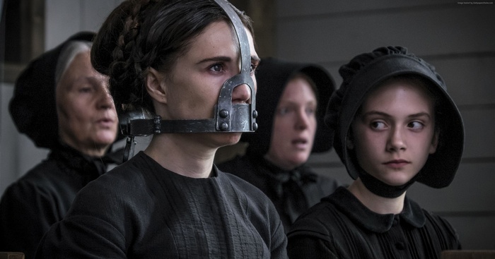 Woman in muzzle with women in bonnets