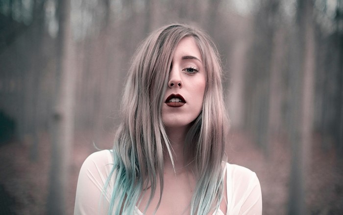 Woman with blonde and blue hair in a forest