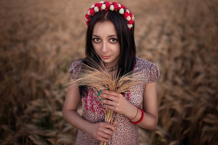 Woman with flower crown holding wheat in a field