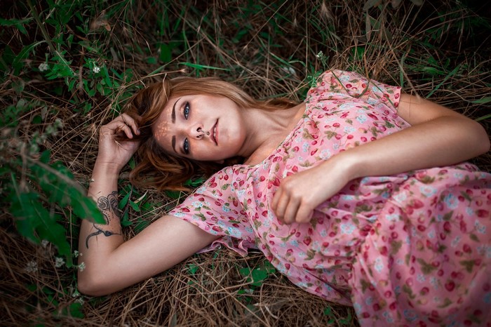 Woman with nose ring lying in grass wearing pink dress