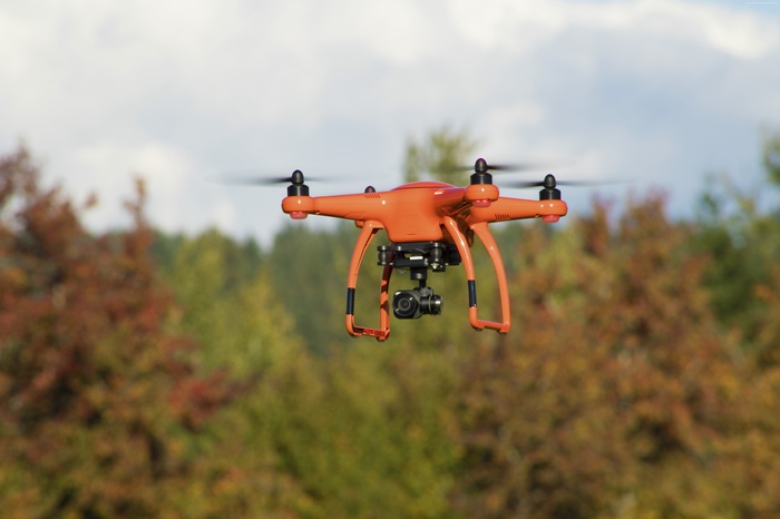 Orange drone with camera flying outdoors