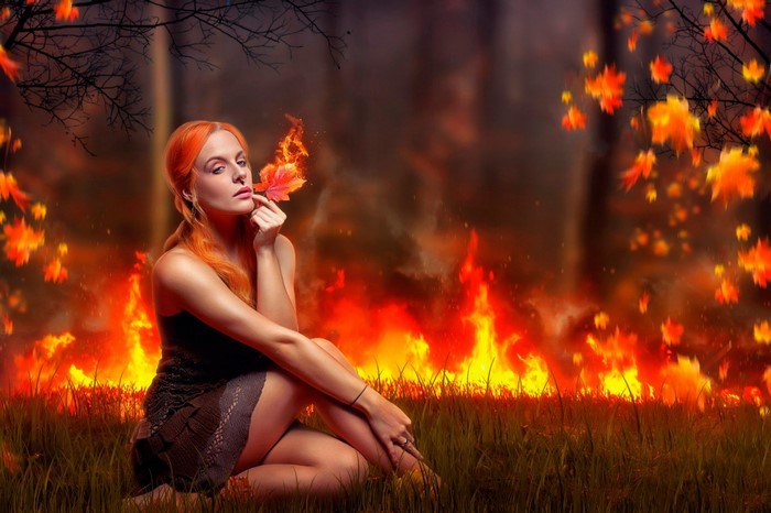 Woman with fiery leaf in burning forest