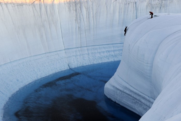 Two climbers rappelling down a glacial crevasse
