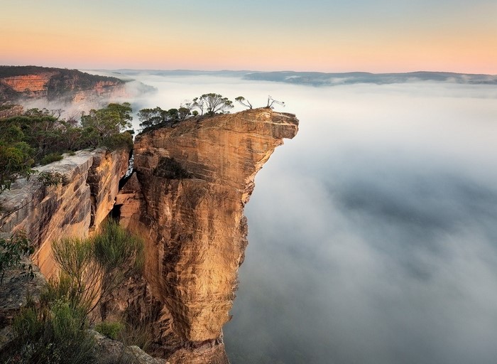 Cliff overlooking misty valley at sunrise