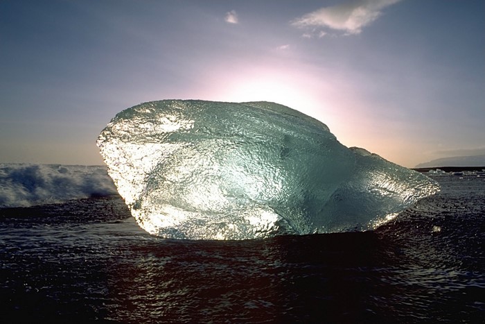 Iceberg on a beach at sunset with waves