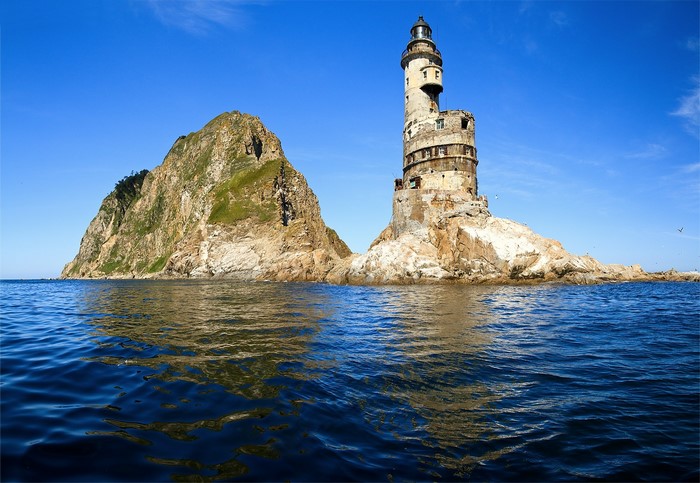 Abandoned lighthouse on a rocky island in the sea