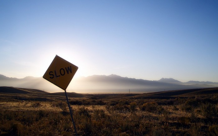 Yellow 'SLOW' sign in a desert landscape at sunrise