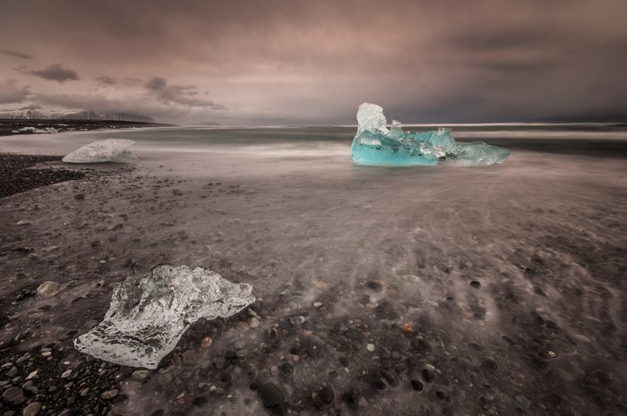 Icebergs on a black sand beach with ocean waves