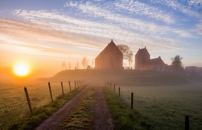 Sunrise over a misty landscape with a church
