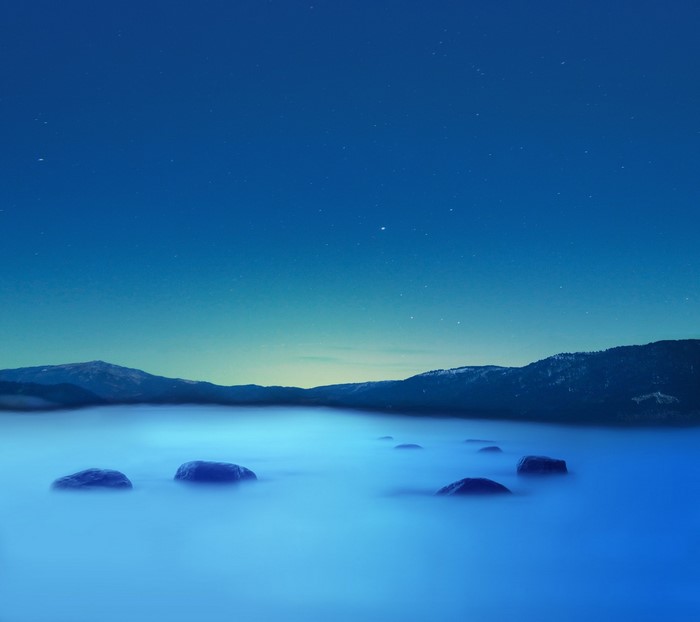 Rocks in foggy lake under starry night sky