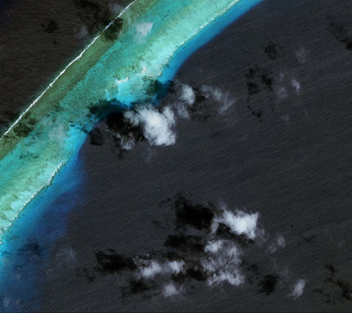 Aerial view of a coral reef and ocean with clouds