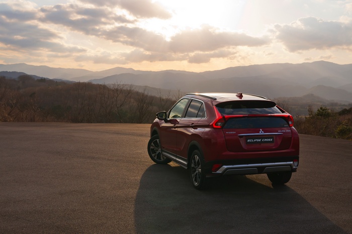 Red Mitsubishi Eclipse Cross parked on asphalt with mountains background