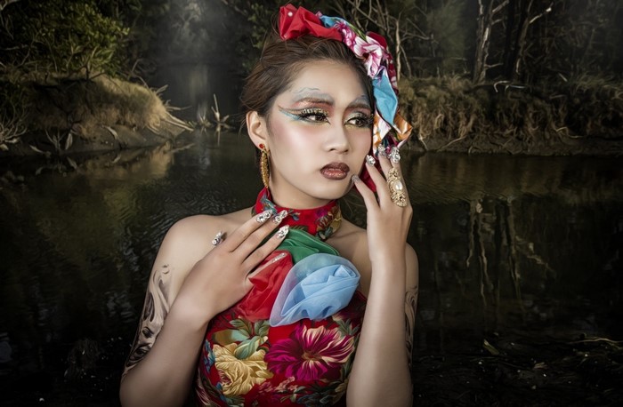 Woman with elaborate makeup and floral dress in a forest