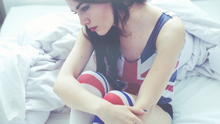 Woman in Union Jack top and knee-high socks on bed
