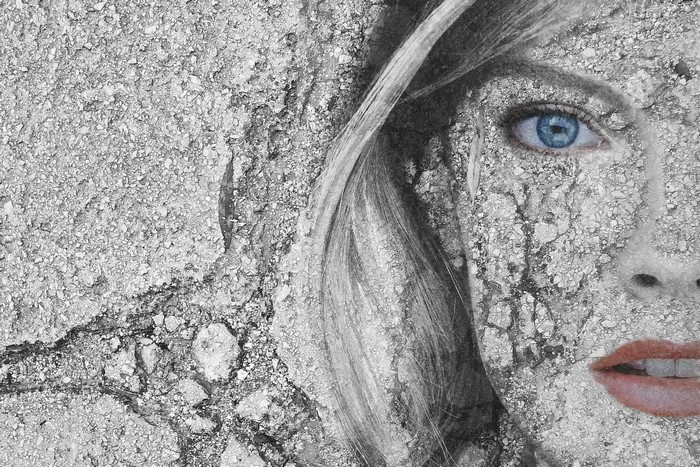 Woman's face covered in cracked stone texture