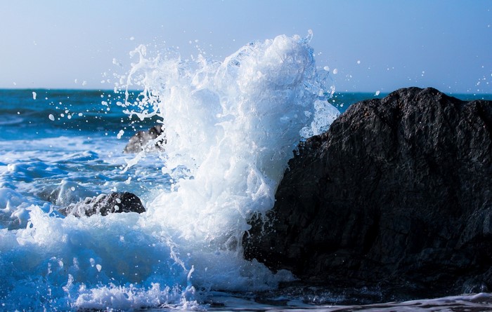 Wave crashing on a dark rock at the sea